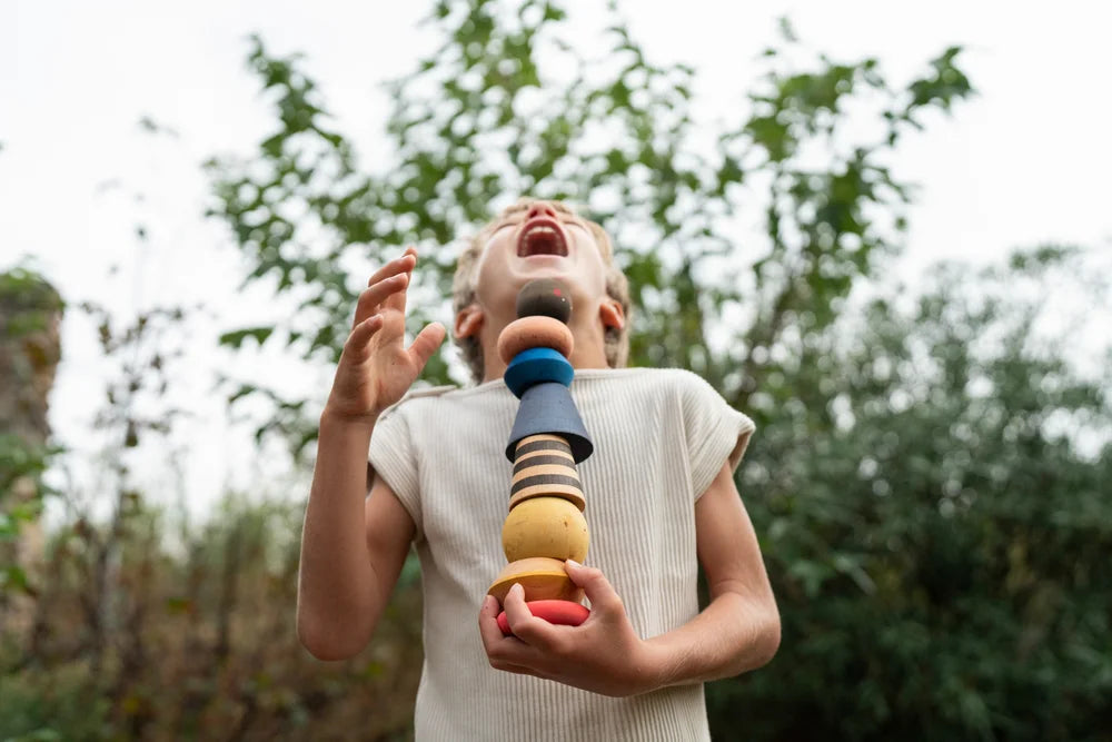 Kind hält buntes Holzspielzeug Grapat serendipity im Freien