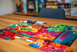 GROLL Frosted Games Brettspiel mit farbigen Spielplanteilen und Komponenten auf Holztisch