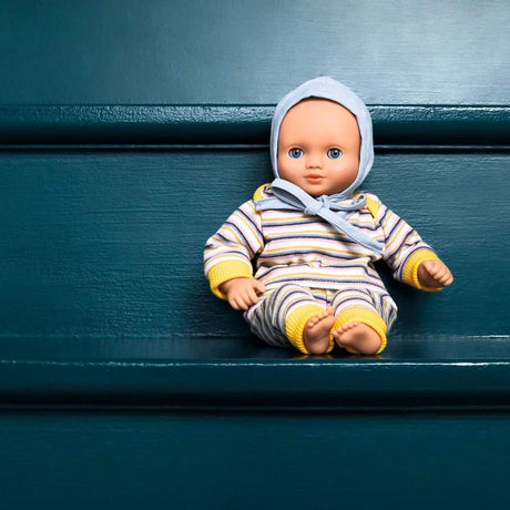Baby Puppe Canary von Pomea in gestreiftem Outfit mit Kopftuch ; POMEA Puppe Canary in gelb-blauem Streifenpyjama mit grauem Häubchen ; POMEA Puppe Canary in gestreifter Kleidung auf Holzbank sitzend ; Pomea Puppe Canary 32cm mit Schlafaugen und gestreiftem Outfit ; POMEA Puppe Canary mit blauem Auge sitzt im hellblauen Outfit