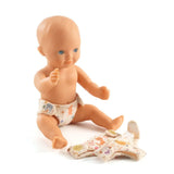 POMEA Puppe 3 Windeln mit bunten Mustern und Tiermotiven ; Pomea Puppe mit 3 waschbaren Windeln von Djeco ; POMEA Puppe 3 Windeln mit Katzen und Blumenmotiven in Creme ; POMEA Puppe sitzt mit Windel und Kleidung neben Windeln ; # POMEA Puppe mit drei farbenfrohen Windeln in Creme und Orange