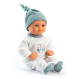 POMEA Puppe Neige mit weißem Strampler und türkisem Mütze sitzend ; POMEA Puppe Neige 32cm von Djeco mit grauer Mütze und weißem Body ; POMEA Puppe Neige - Babypuppe mit hellhäutiger Gesichtspartie, blauen Augen und kariertem Outfit ; POMEA Puppe Neige in grauem Bettchen mit Zubehör auf rosa Teppich