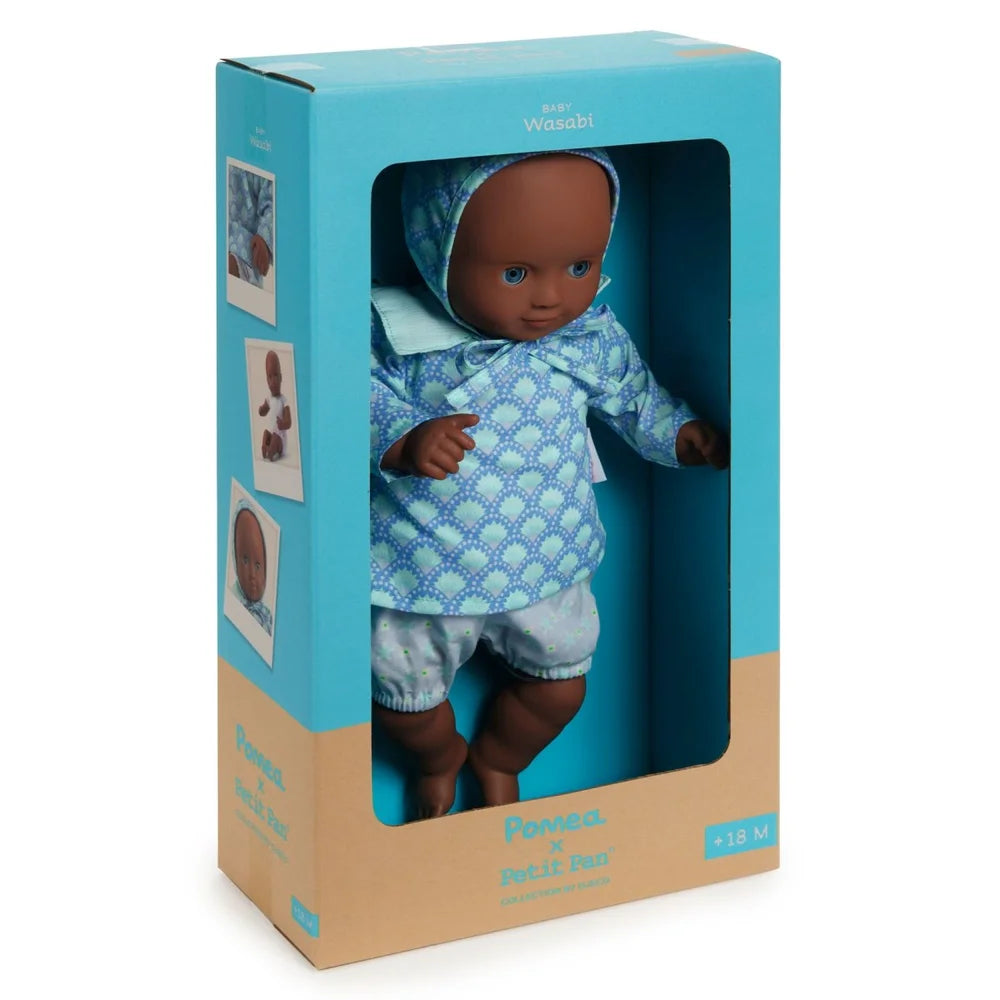 POMEA Puppe Wasabi in blauem Outfit mit Kopftuch in Verpackung ; Pomea x Petit Pan Puppe 32cm mit Schlafaugen und blauem Outfit ; POMEA Puppe Wasabi mit blauem Outfit und Haube sitzt ; POMEA Puppe Wasabi mit brauner Haut, blauen Augen, weißem Outfit sitzend
