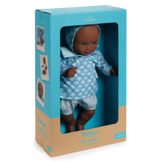 POMEA Puppe Wasabi in blauem Outfit mit Kopftuch in Verpackung ; Pomea x Petit Pan Puppe 32cm mit Schlafaugen und blauem Outfit ; POMEA Puppe Wasabi mit blauem Outfit und Haube sitzt ; POMEA Puppe Wasabi mit brauner Haut, blauen Augen, weißem Outfit sitzend
