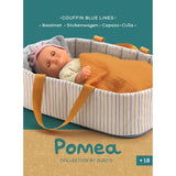 POMEA Puppentragetasche Blue Lines mit Puppe und Zubehör ; # POMEA Puppentragetasche mit orangenen Griffen und gestreiftem Design ; Kleines Kind mit POMEA Puppentragetasche Blue Lines und Puppe auf gelbem Sofa. ; POMEA Puppentragetasche Blue Lines mit Zubehör, Djeco Kollektion ; Puppentragetasche mit Puppe, gestreiftem Design und orangefarbenen Henkeln