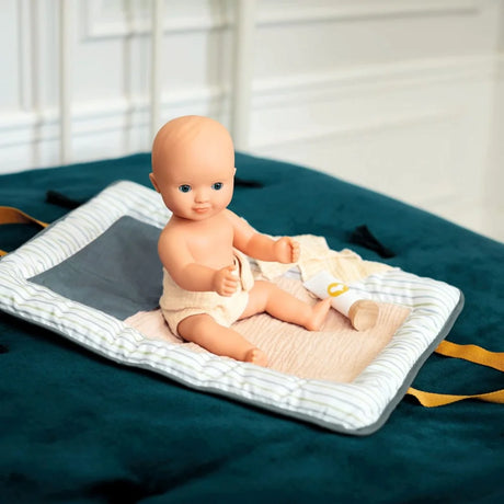 POMEA Badepuppe Mädchen Prune in rosa-weißem Kleid mit Mütze ; POMEA Badepuppe Mädchen Prune mit rosa Badeanzug und Stirnband ; POMEA Badepuppe Baby Prune 32cm mit rosa Outfit und Kopftuch ; POMEA Badepuppe Mädchen Prune liegt auf Wickelunterlage auf Tuch ; Kleines Mädchen mit POMEA Badepuppe in Rosa spielend auf Bett ; Mädchen mit POMEA Badepuppe in rosa Puppenkleidung spielend ; POMEA Badepuppe Mädchen Prune mit Zubehör beim Baden spielen